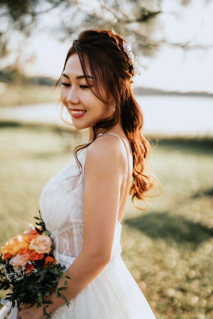 A bride in a white dress gracefully holds a vibrant bouquet, radiating joy and elegance on her special day.