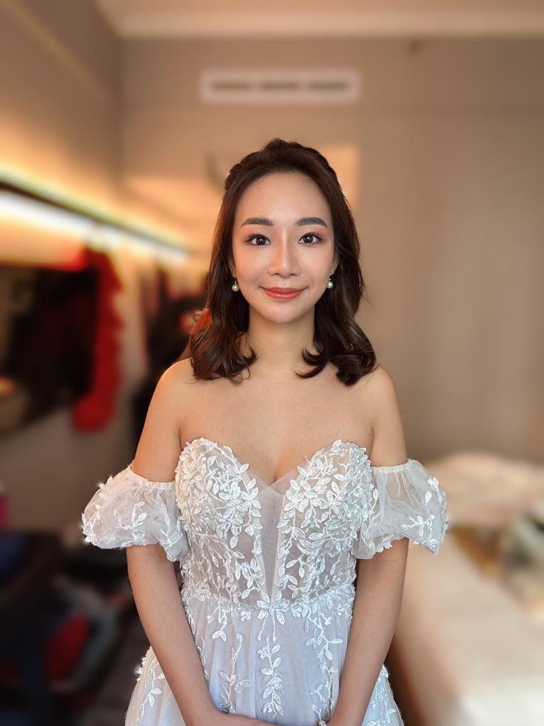 A woman in a wedding dress elegantly poses for a photo, showcasing her joyful expression and beautiful attire.