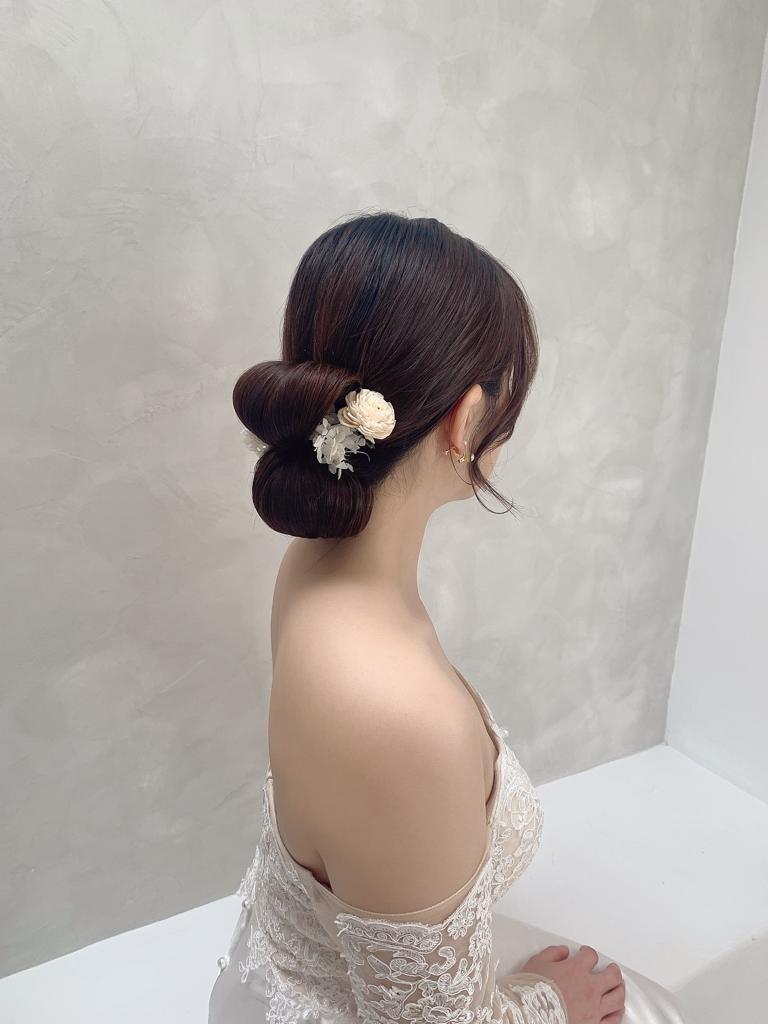 A woman in a white dress adorned with a flower in her hair, exuding elegance and grace.