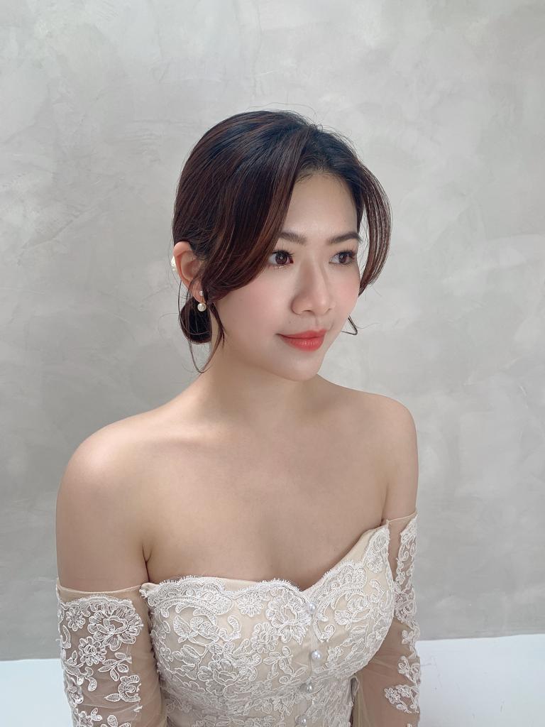 Bride with a soft chignon, off-shoulder lace gown and coral lip