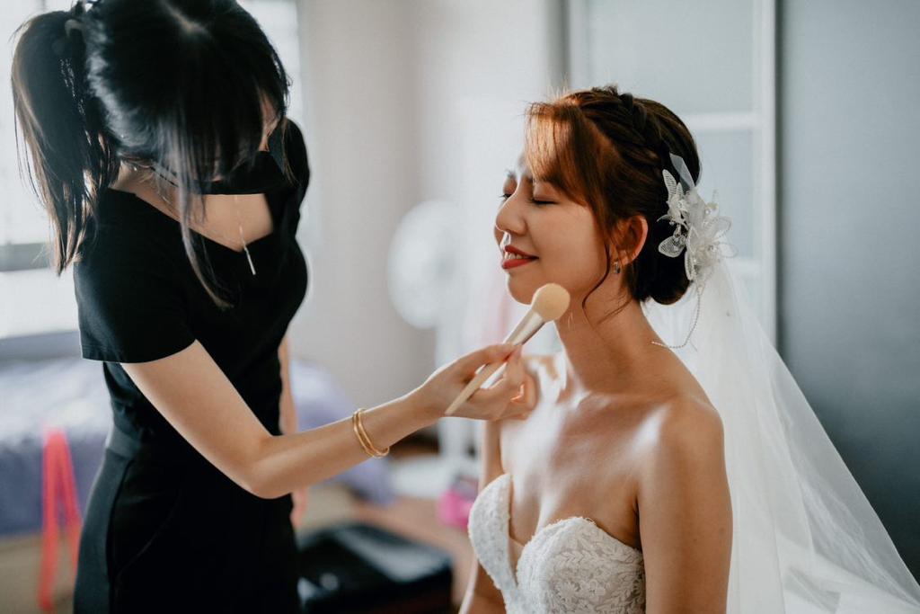 Behind-the-scenes — final powder touch-ups on a bride in veil and strapless gown