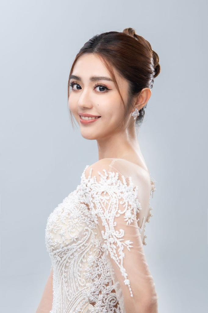 Smiling bride with a braided bun updo and a pearl-detail lace gown