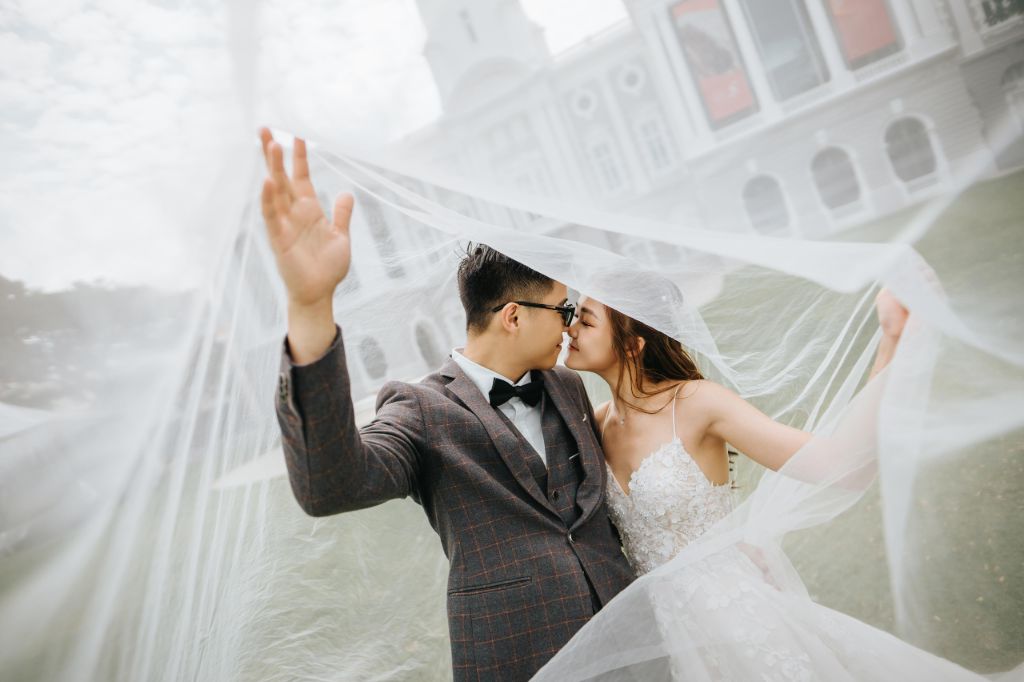 Couple kissing beneath a flowing veil at a heritage building