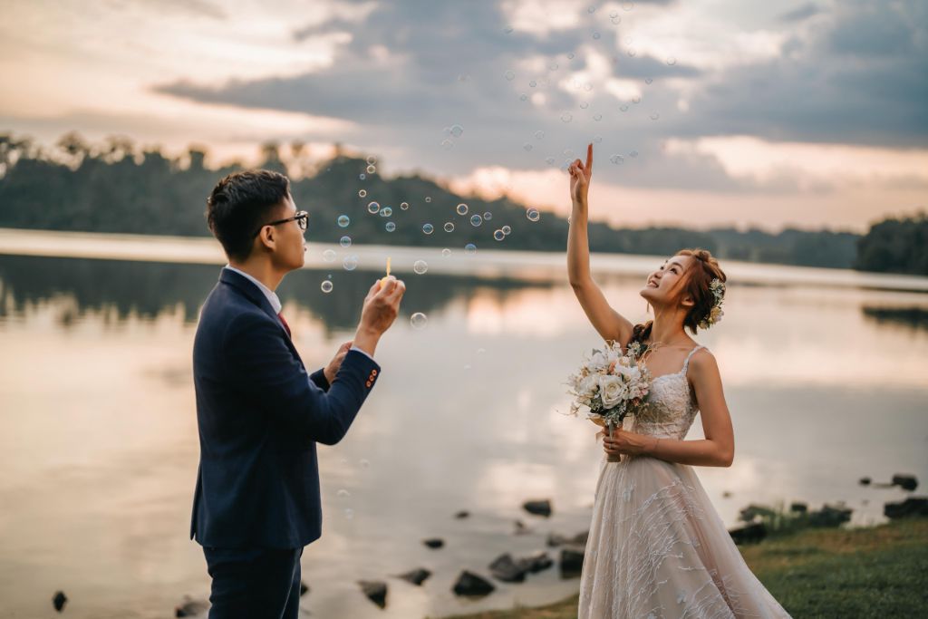 Pre-wedding photo at a lake with bubbles at sunset