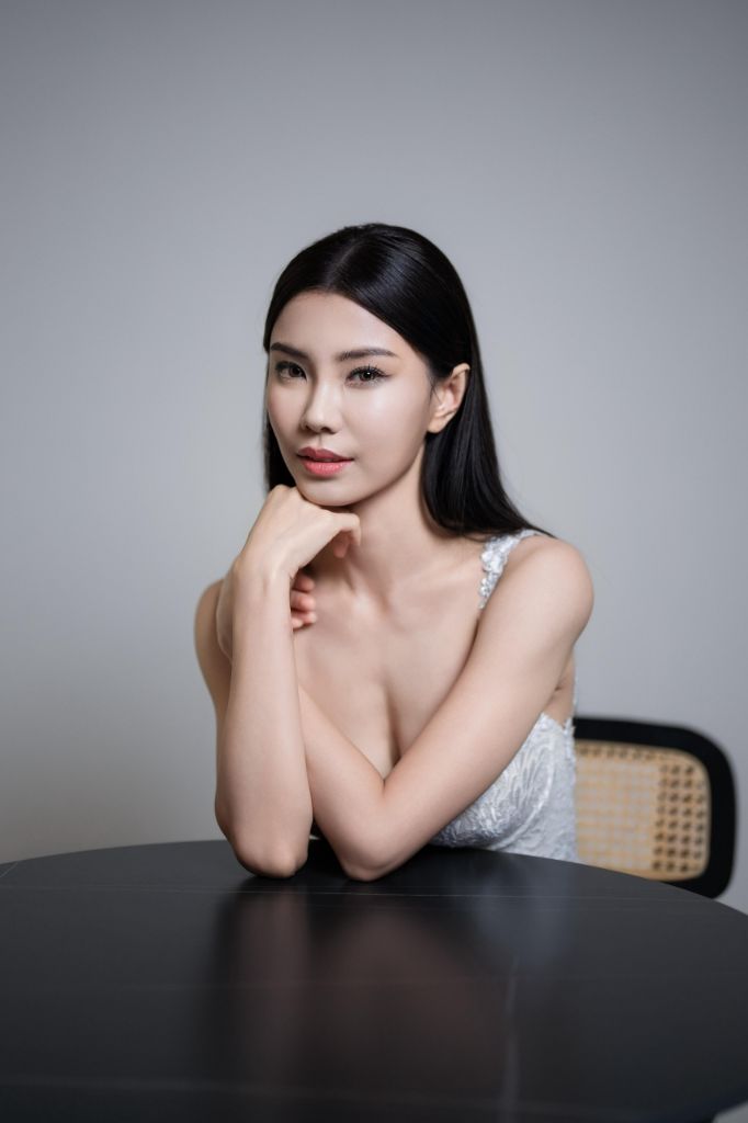 Bride seated with sleek straight hair, soft natural makeup and lace gown